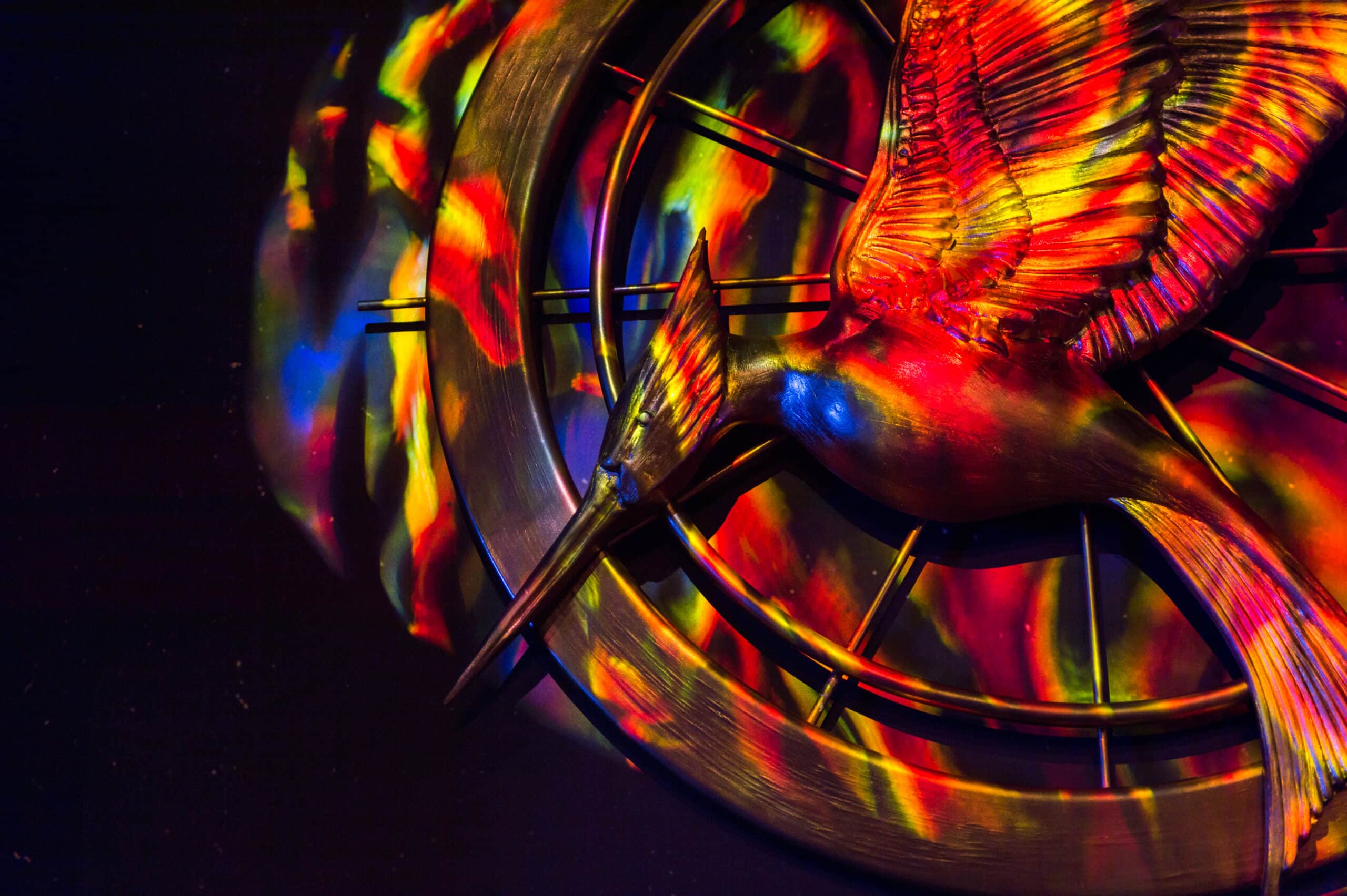Hunger Games mocking jay symbol in red, green, and blue lighting.