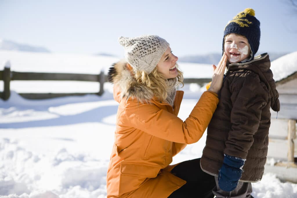 Mother applying sunscreen on son in winter