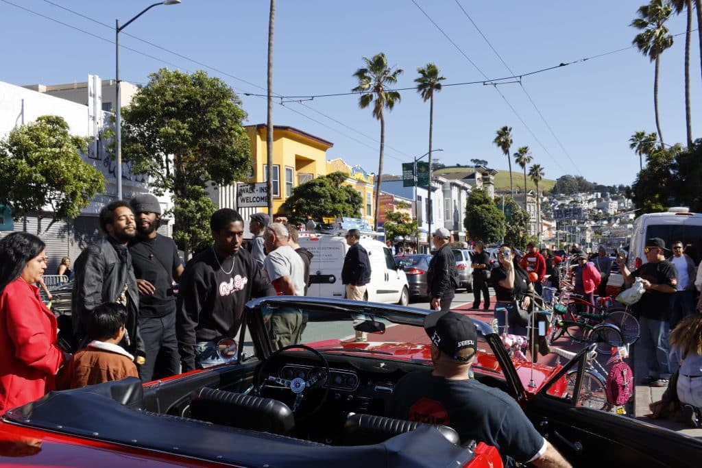 people gathering around red lowrider.