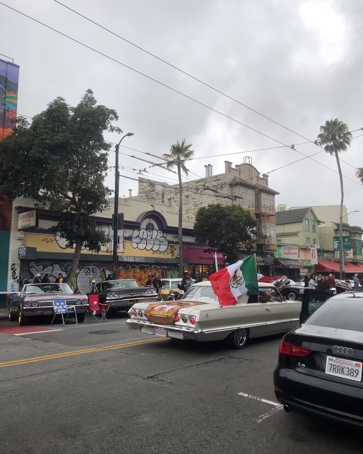 white lowrider with Mexico flag flying out the window.