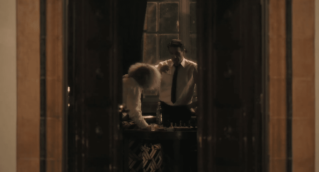 a man leaned over a chess board, a shot from the queen's gambit