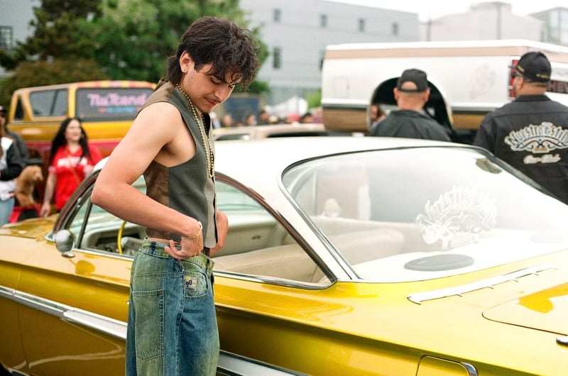 A local standing in front of yellow lowrider.