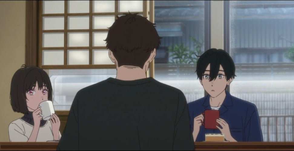 Kengo sits with his back facing the viewer. In the background, Kobato and Osanai face him, sipping their cocoa and watching him.