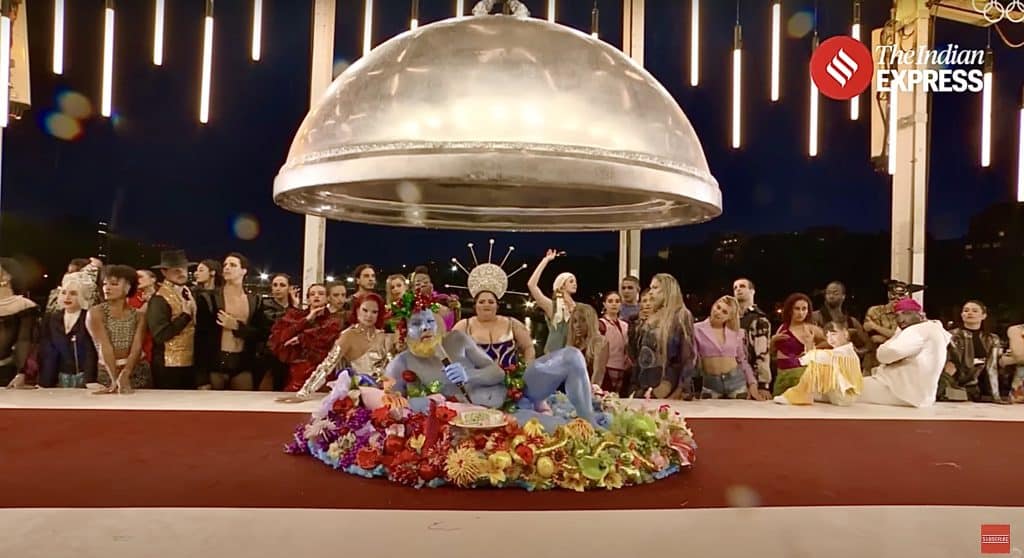 A screenshot of the opening ceremony's most controversial scene. A half-naked blue man lies on a dinner platter in front of a group of drag queens.