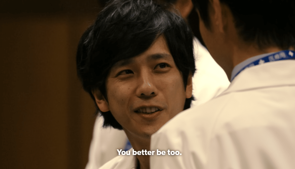 Tokai portrayed by Kazunari Ninomiya smirks at another doctor. Bottom text reads "You better be too."