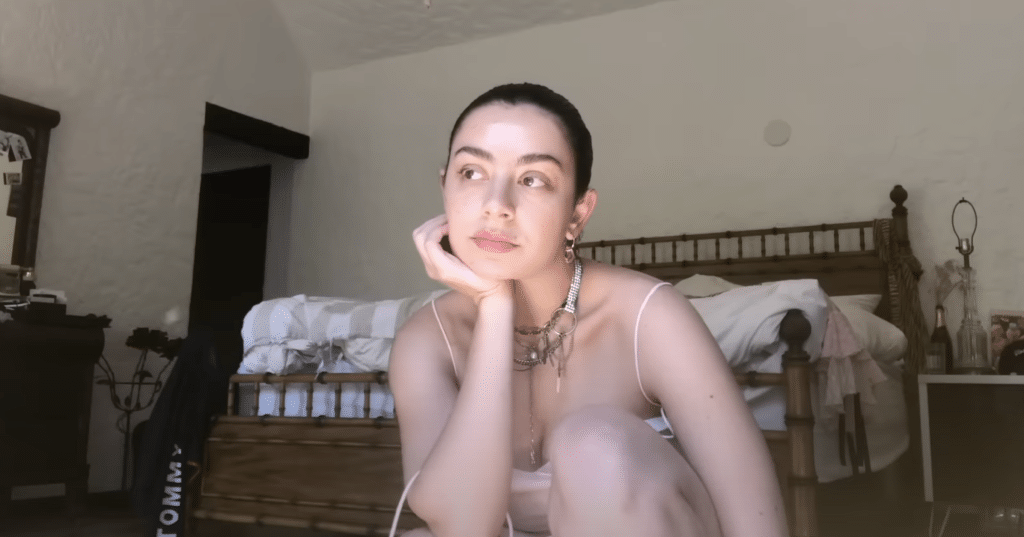 Charli XCX sitting in front of her bed