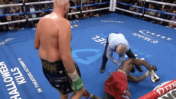 Tyson Fury looking over a knocked out Deontay Wilder