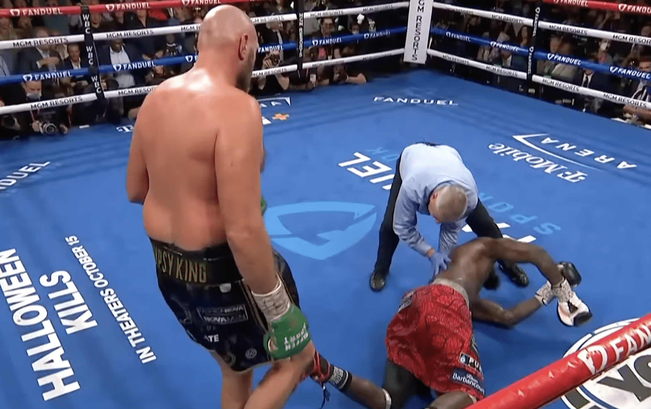 Tyson Fury looking over a knocked out Deontay Wilder
