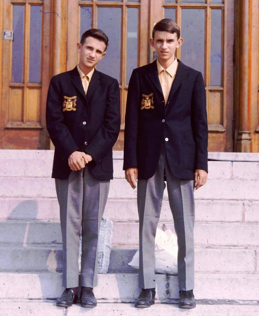 Boys standing in private school uniforms in from of academic institution.