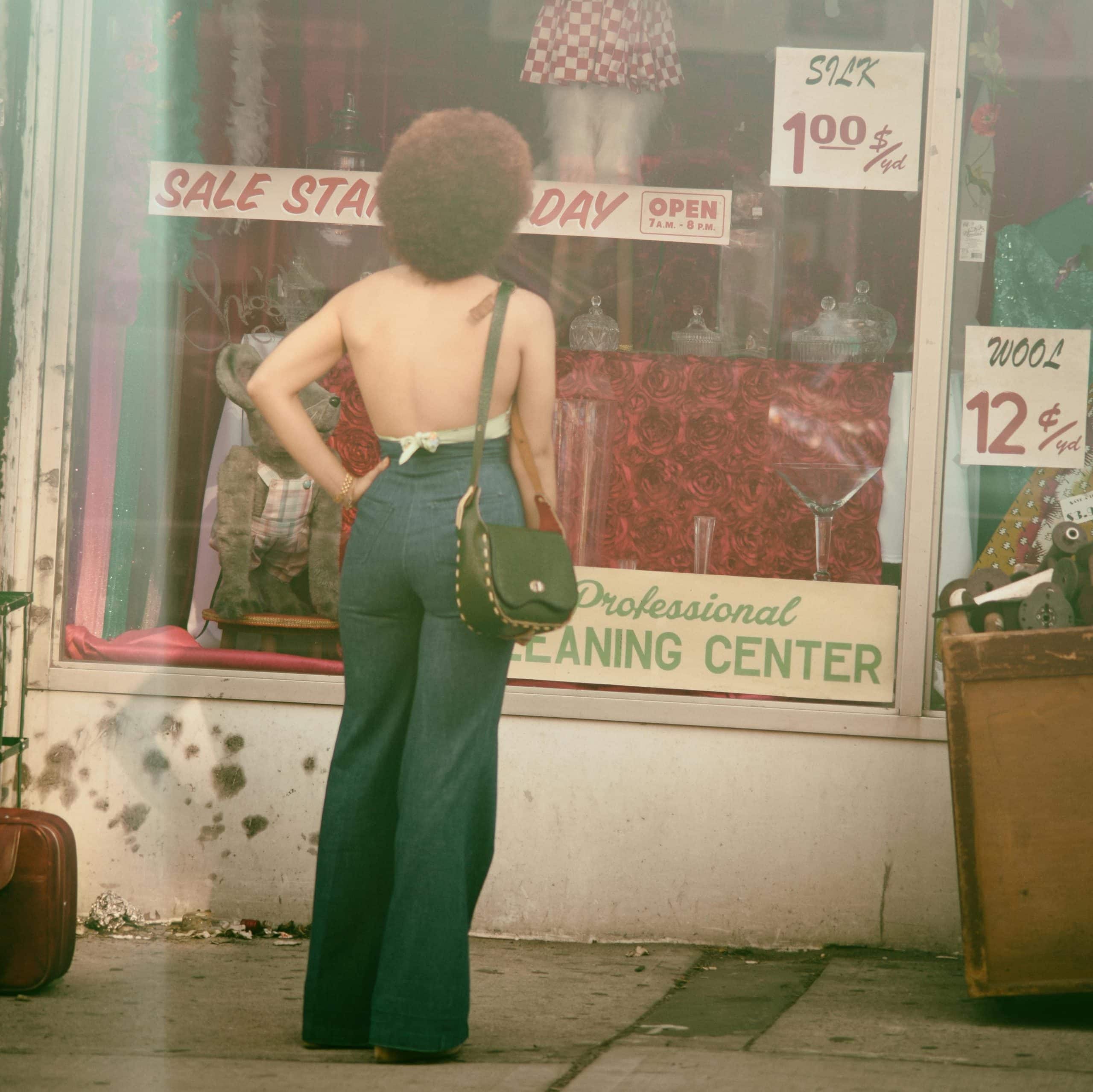 Woman from 70s dressed in high-wisted flared jeans and a halter top, with back turned - corporate fashion