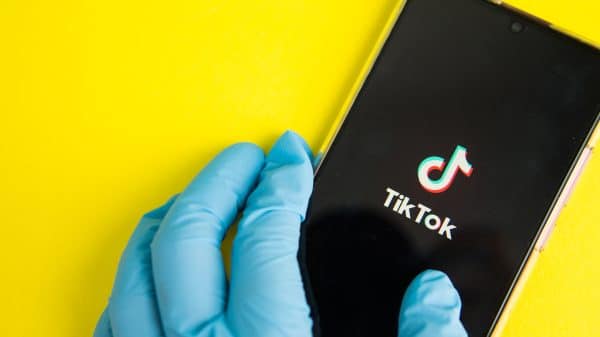 Hands in medical gloves holding a phone that displays TikTok where Gen Z receives their heal information.
