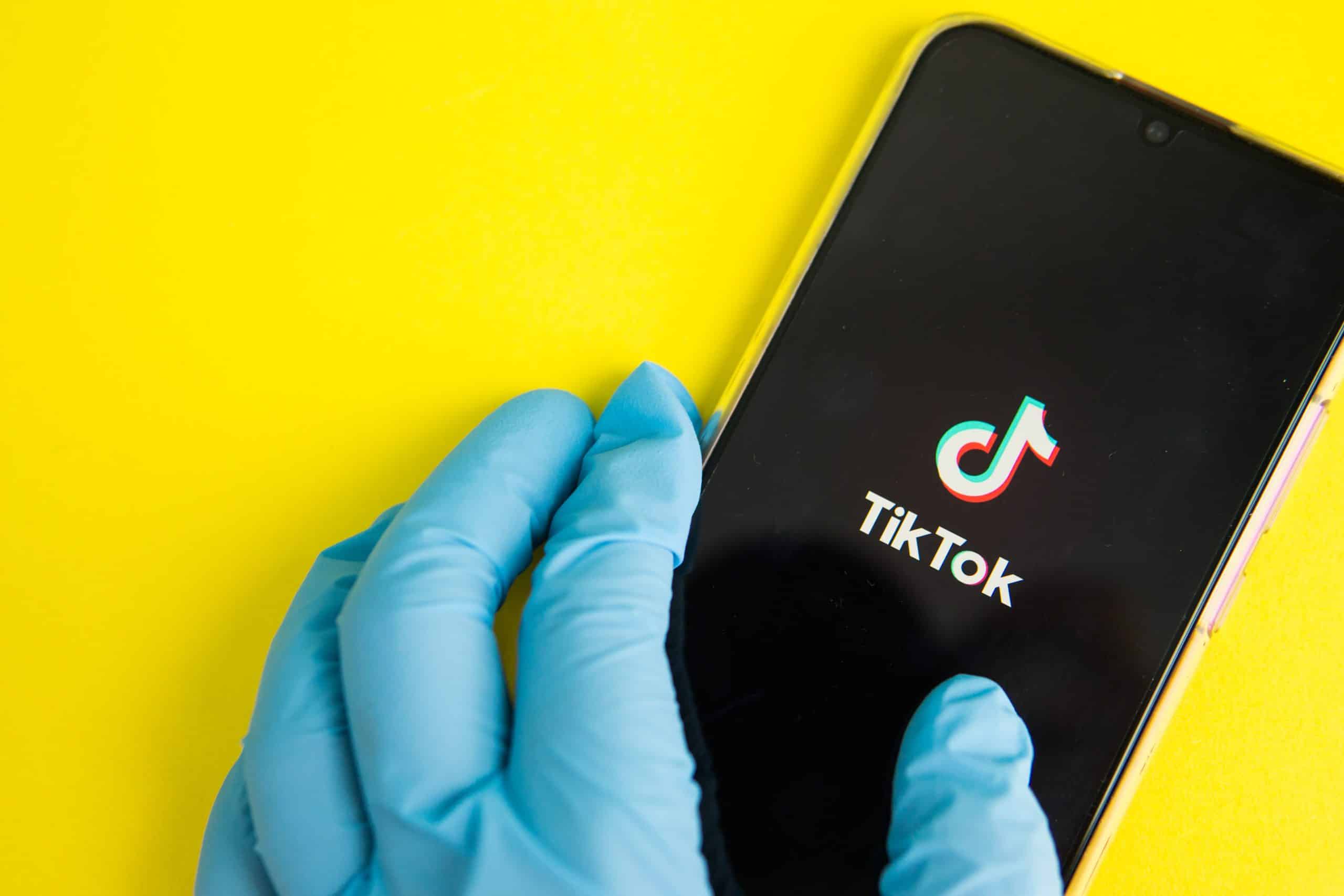 Hands in medical gloves holding a phone that displays TikTok where Gen Z receives their heal information.