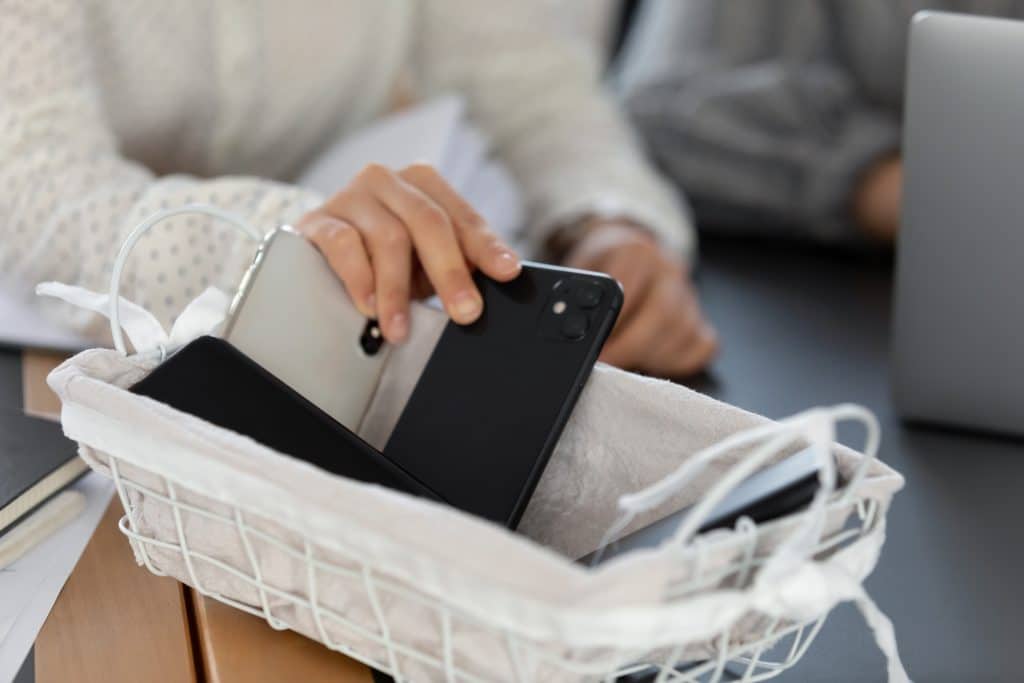Phones being removed from students and placed into a basket