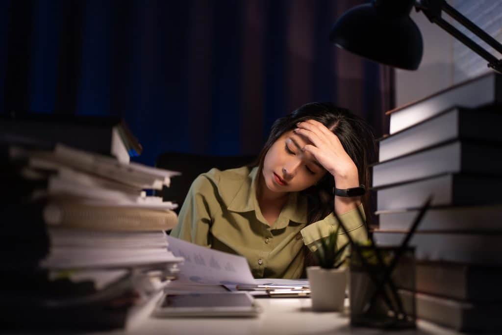 young woman stressed with homework around her