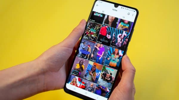 Two hands hold a phone showing a feed of videos on TikTok