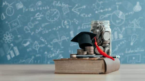 An image with a white board, coins, a book, and a graduation cap.