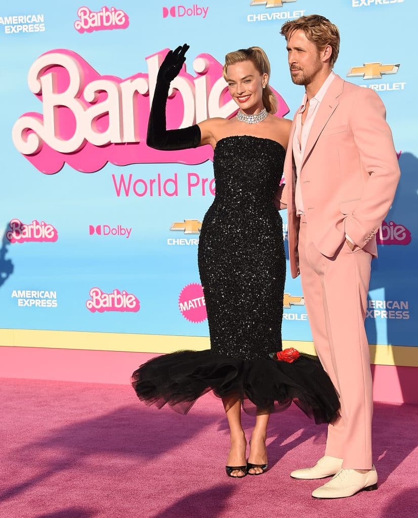 Margot Robbie in a black dress and Ryan Gosling in a pink suit promoting Barbie
