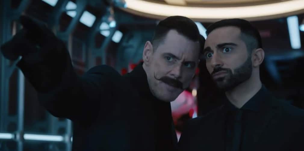 Eggman (Sonic Movie 1) points to the left off camara while leaning towards a wide-eyed Stone.