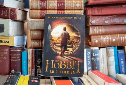 Copy of The Hobbit leaning against other book stacks
