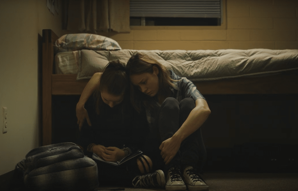 woman and girl are crouched sitting by the bed.