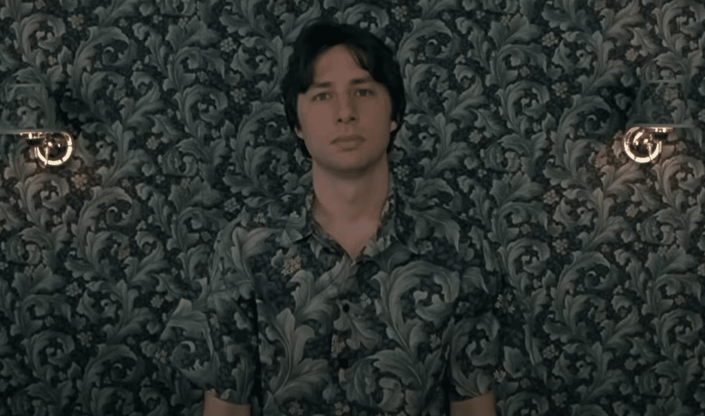 A dude is blending into the wall by wearing a matching shirt.