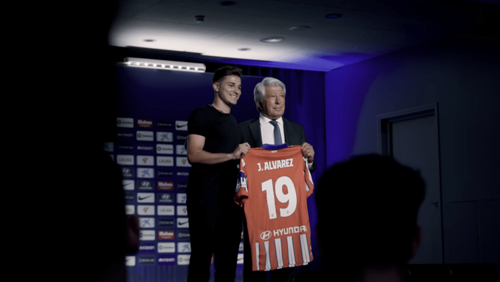 Julian Alvarez holding up new shirt