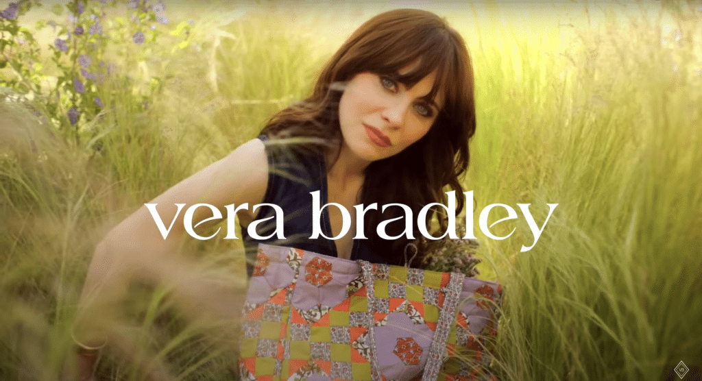 A photo of Zooey Daschenl posing with Vera Bradley's logo underneath.