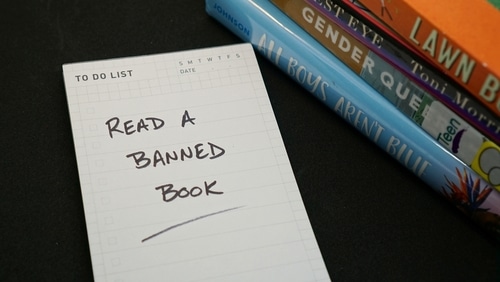 An image of two books and a notepad that says "Read a banned book" for banned books week.