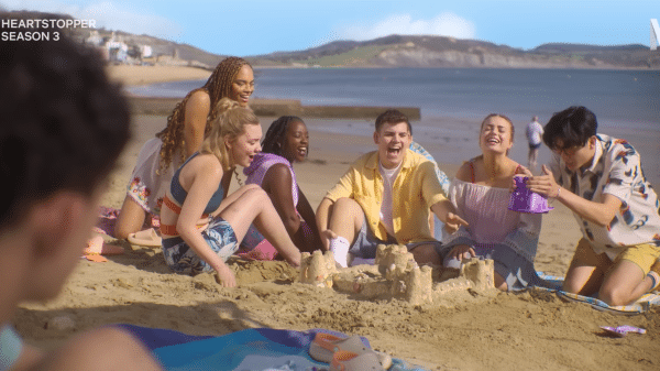 The Heartstopper group together on the beach as Charlie watches.