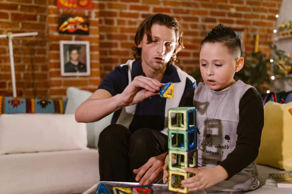 Man stacking colorful blocks with young boy