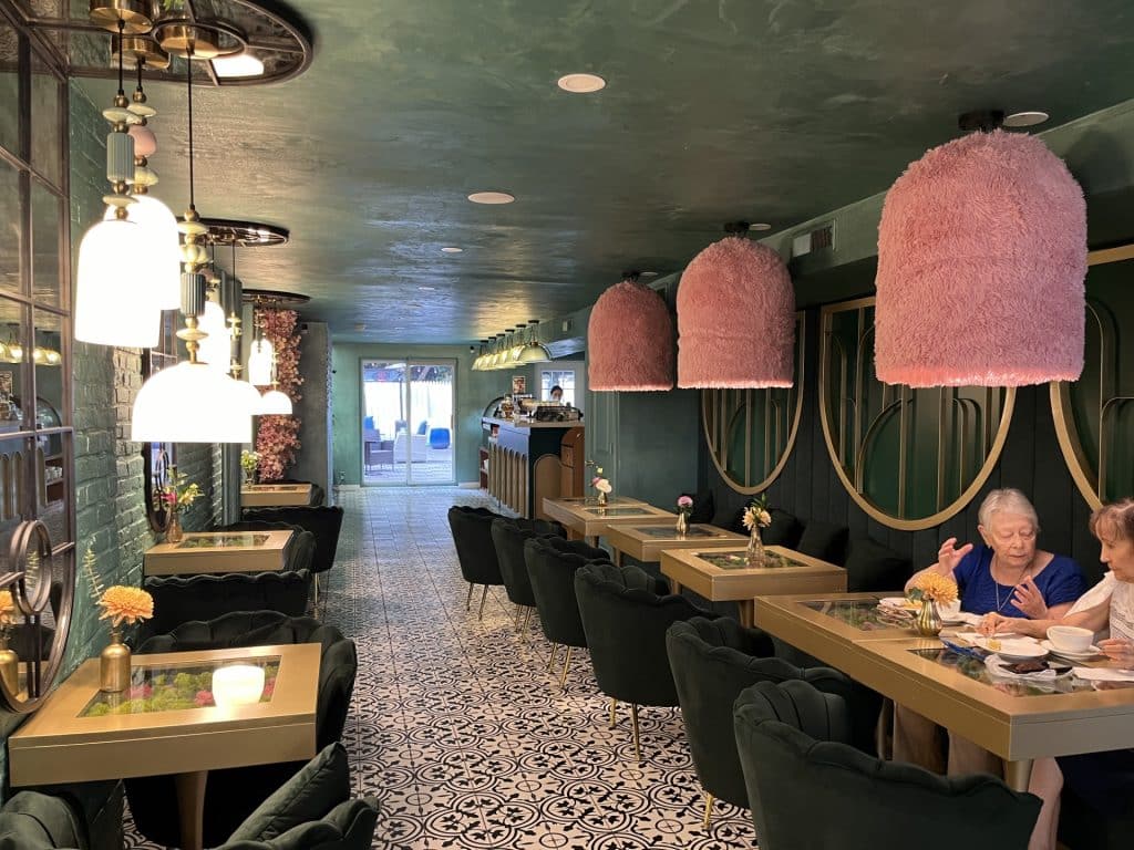 Inside Sahola Cafe with green velvet chairs and pink fuzzy lights.