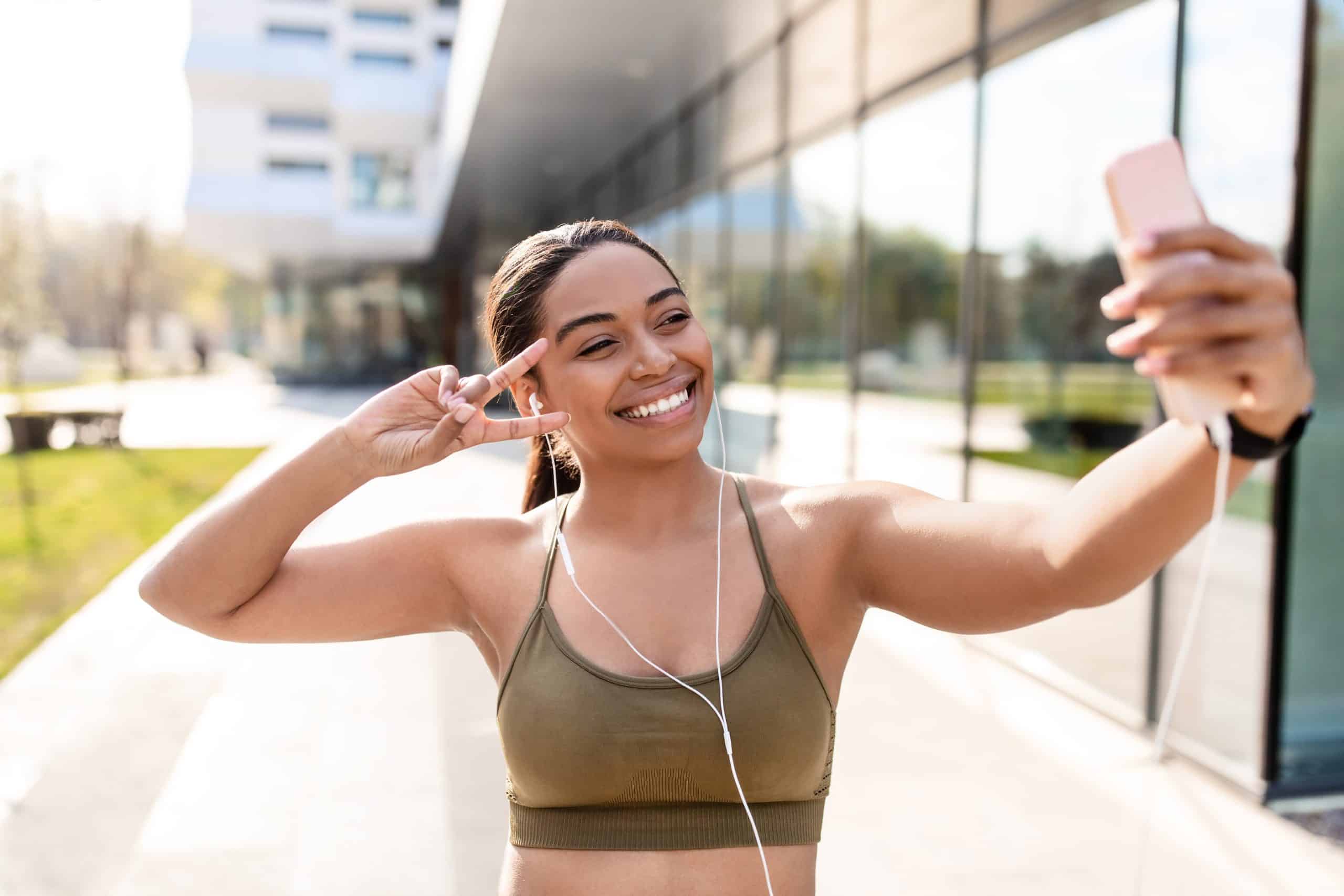 Young woman taking a selfie/ recording a video on the phone on the street