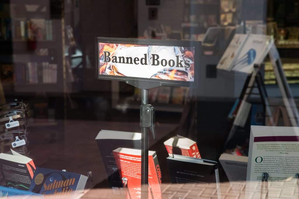 An image of a bookstore window with a "Banned Books" sign for banned books week