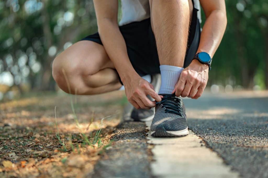 Close up of man tying his shoe laces for a run in the park.