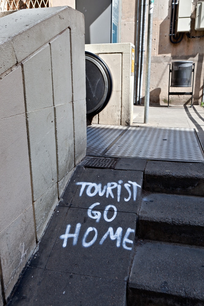 tourists go home spray painted on a pavement
