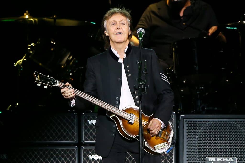 The Beatles member, Paul McCartney, onstage playing a guitar.