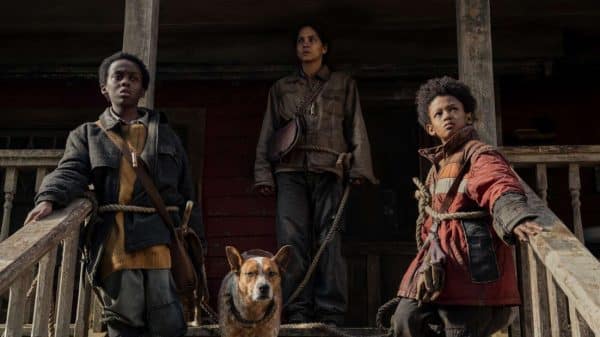 The three main characters of the movie pose on the porch steps with their pet dog.