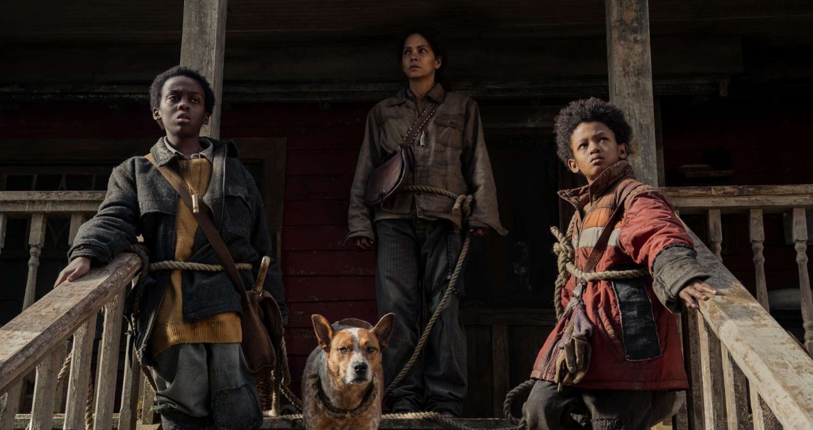 The three main characters of the movie pose on the porch steps with their pet dog.
