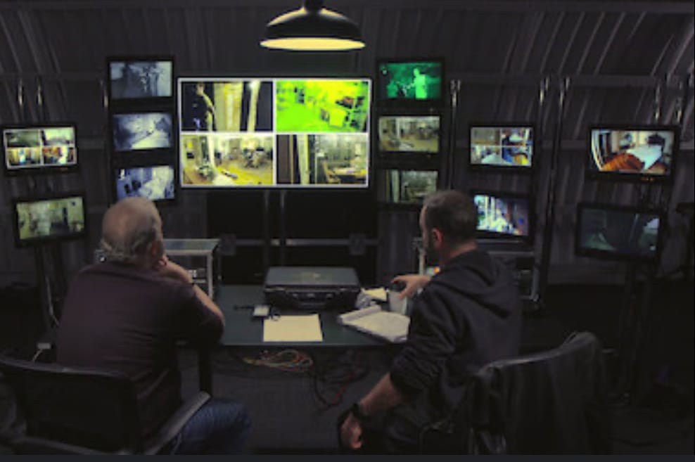 two men sit in front of security cameras to record the horror.