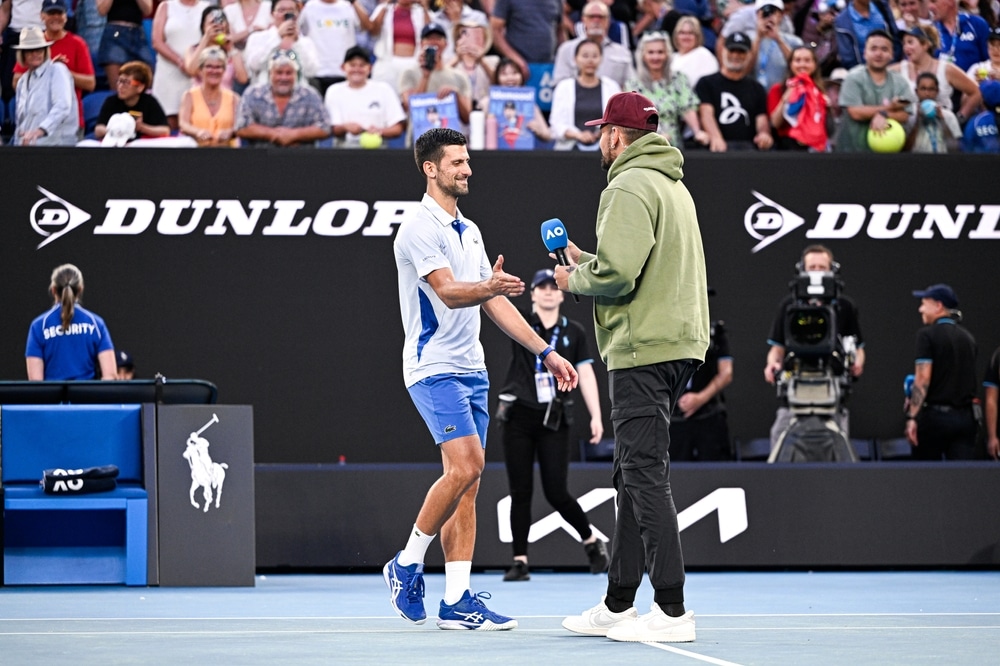 Nick Kyrgios and Novak Djokovic on a tennis court, Kyrgios is interviewing Djokovic