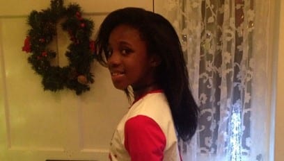 Child turned around facing the camera with christmas reef behind her
