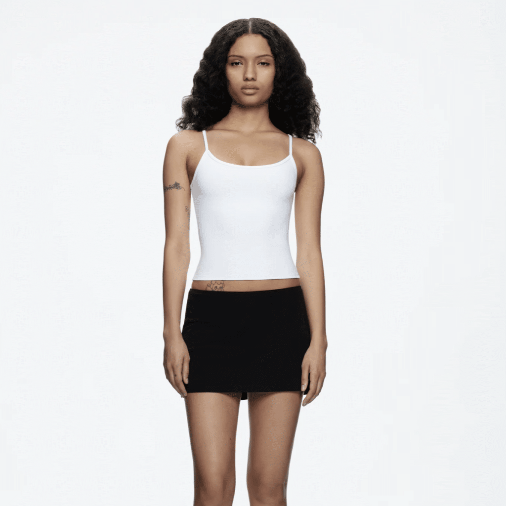 Model in a white tank top and a black Tank Air mini skirt