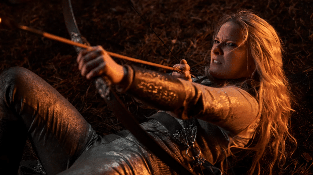 Morfydd Clark as Galadriel, pointing a bow and arrow while on the ground