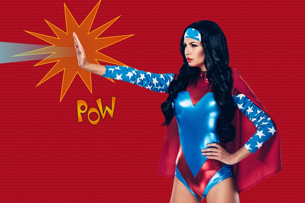 Side profile of a woman in a superhero costume for Halloween, shooting a beam from her hand. The word "POW" can be seen against the red background, representing comic book style.