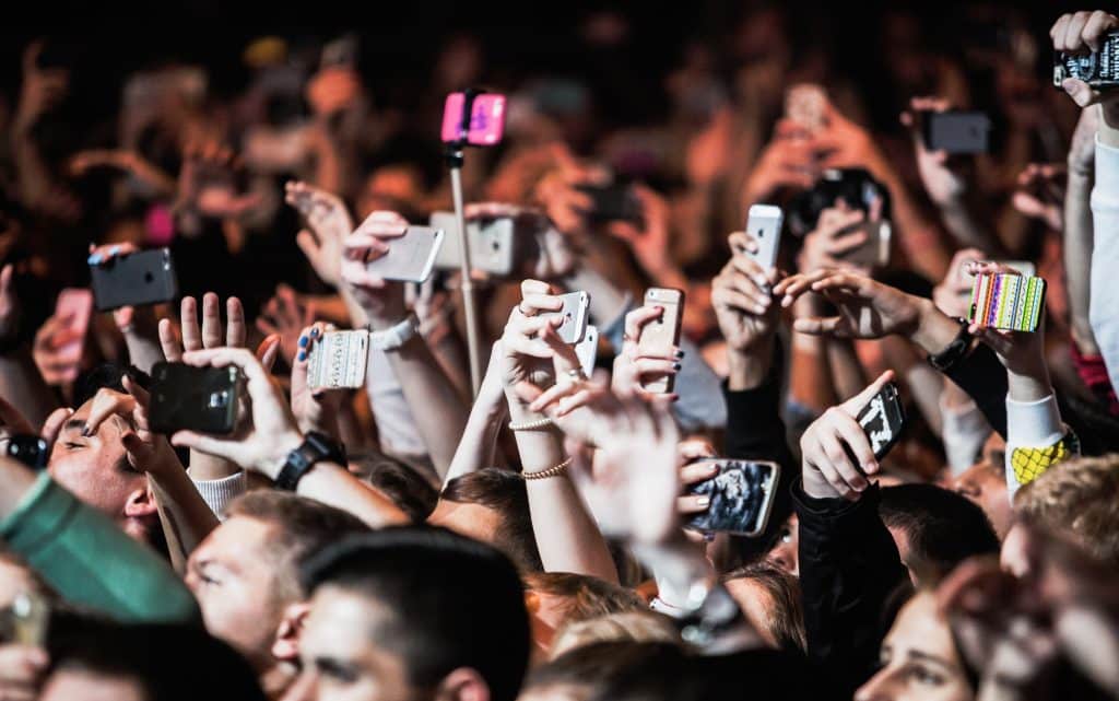 Hands of fans with smart phone mobile camera film dj concert.