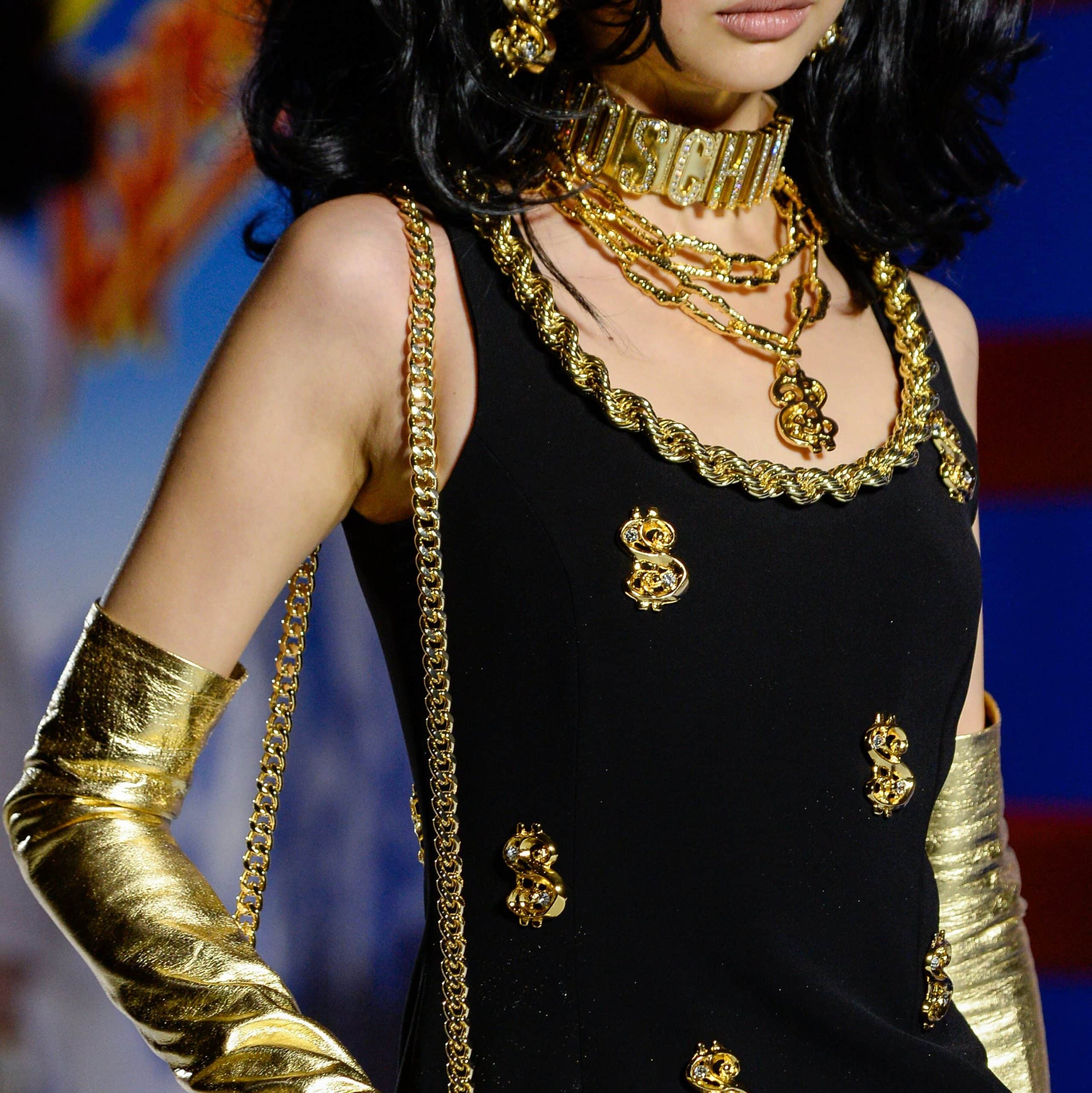 Model in black dress and maximalist gold jewelry.
