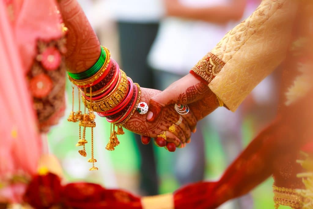 Two intertwined hands with layered jewelry