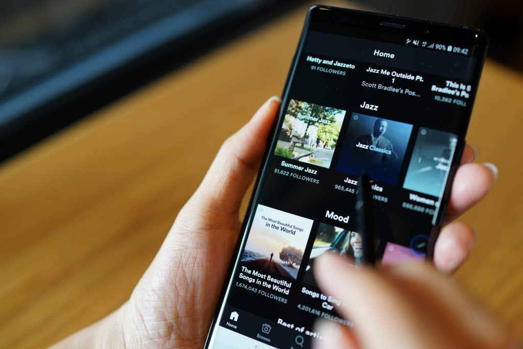 A close-up of someone scrolling through spotify playlists on their phone.
