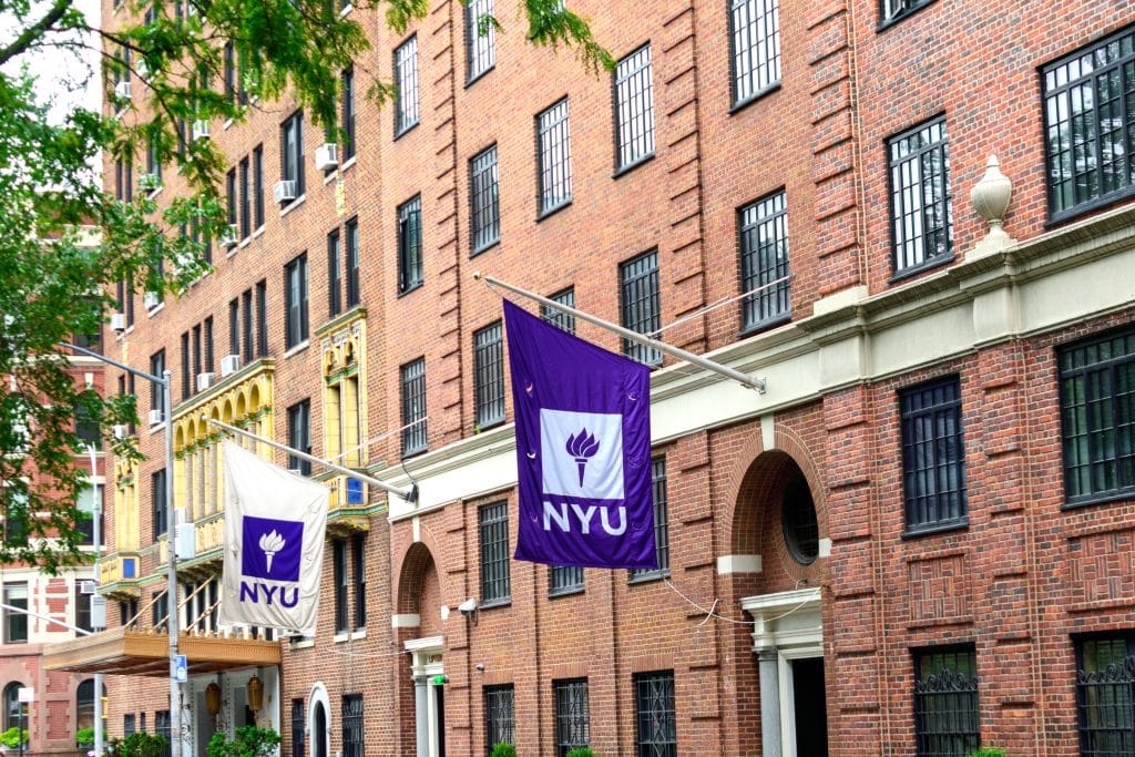New York University brick buildings with two white and purple NYU flags