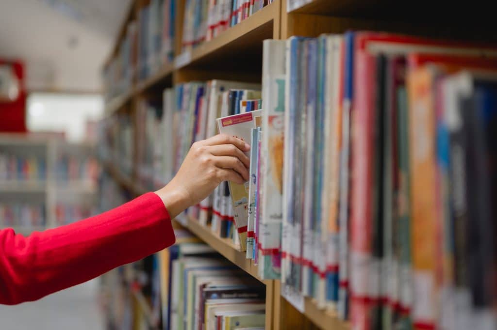 An arm grabbing a book to read from the library